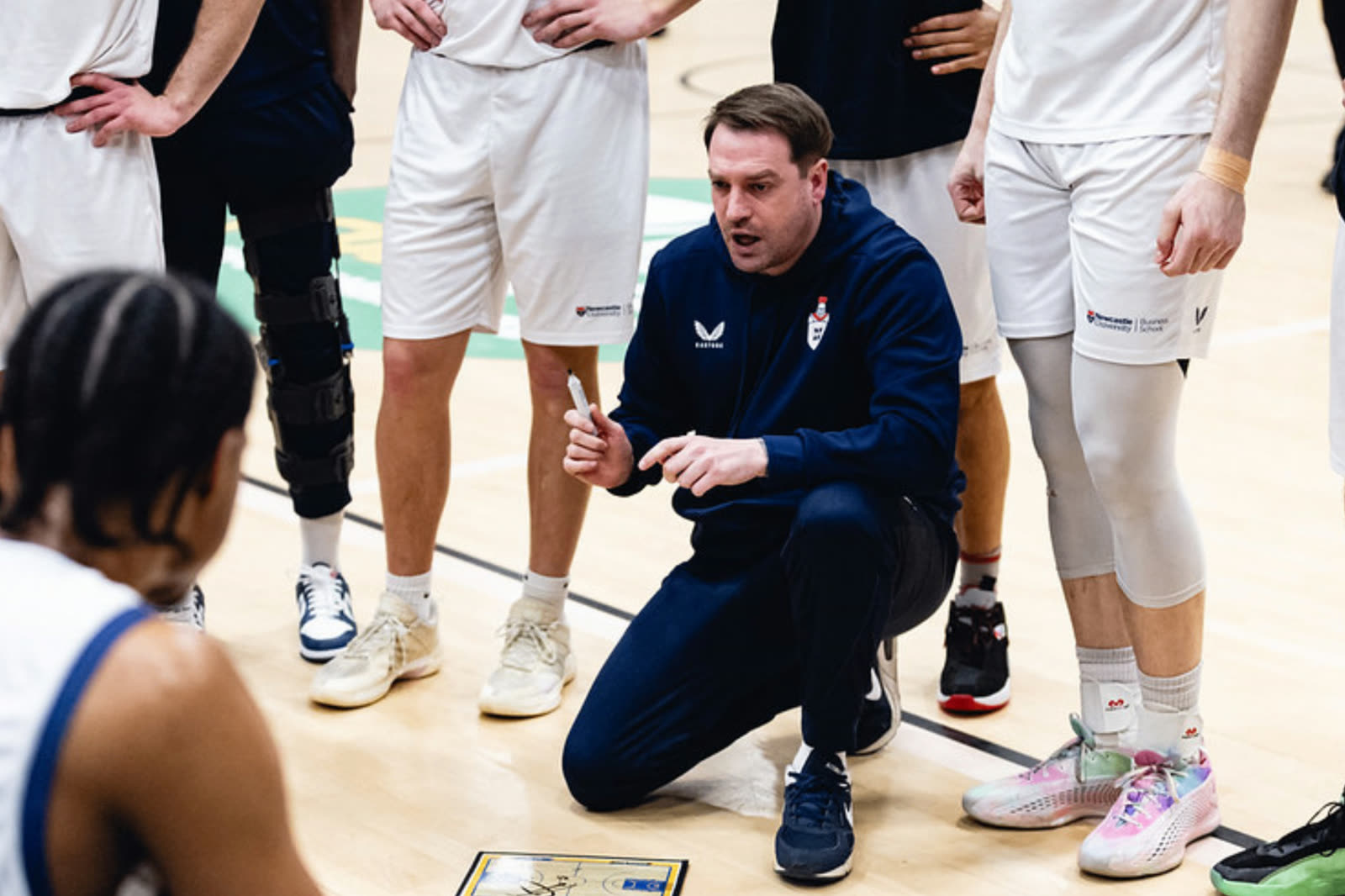 University coach speaking with players during a basketball game timeout
