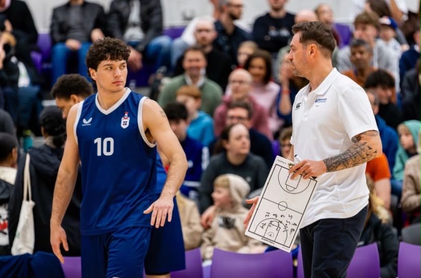 A university basketball coach working with an athlete on court